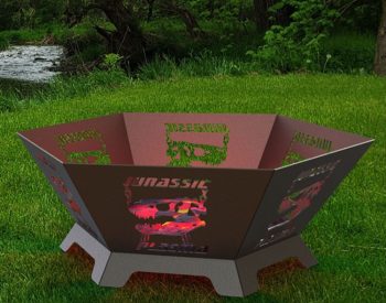Custom plasma-cut steel fire pit with Jurassic Park dinosaur design displayed on grass.