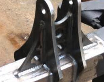 Close-up of a welded steel mounting bracket attached to a square metal tube, showing clean weld beads.